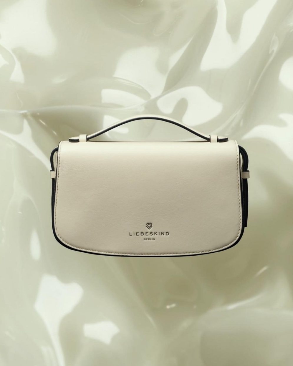 white leather handbag by Liebeskind on milky plexiglass background