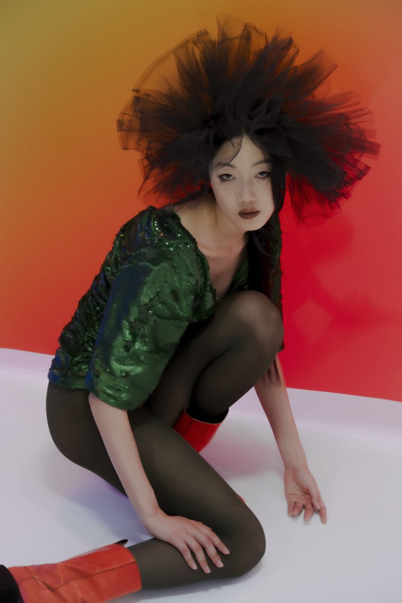 Model Loo Loo, fotografiert von Olga Urbanek vor einem orangefarbenen Hintergrund, hat einen explosiven Haarschnitt